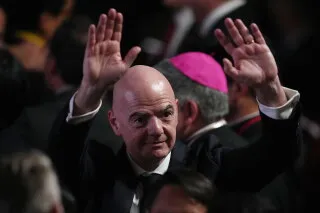 رئيس FIFA جياني إنفانتينو يرفع يديه وسط حشد، في سياق أزمة بيع حصص كأس العالم ورفض الاتحادات الكبرى لهذه الخطط.