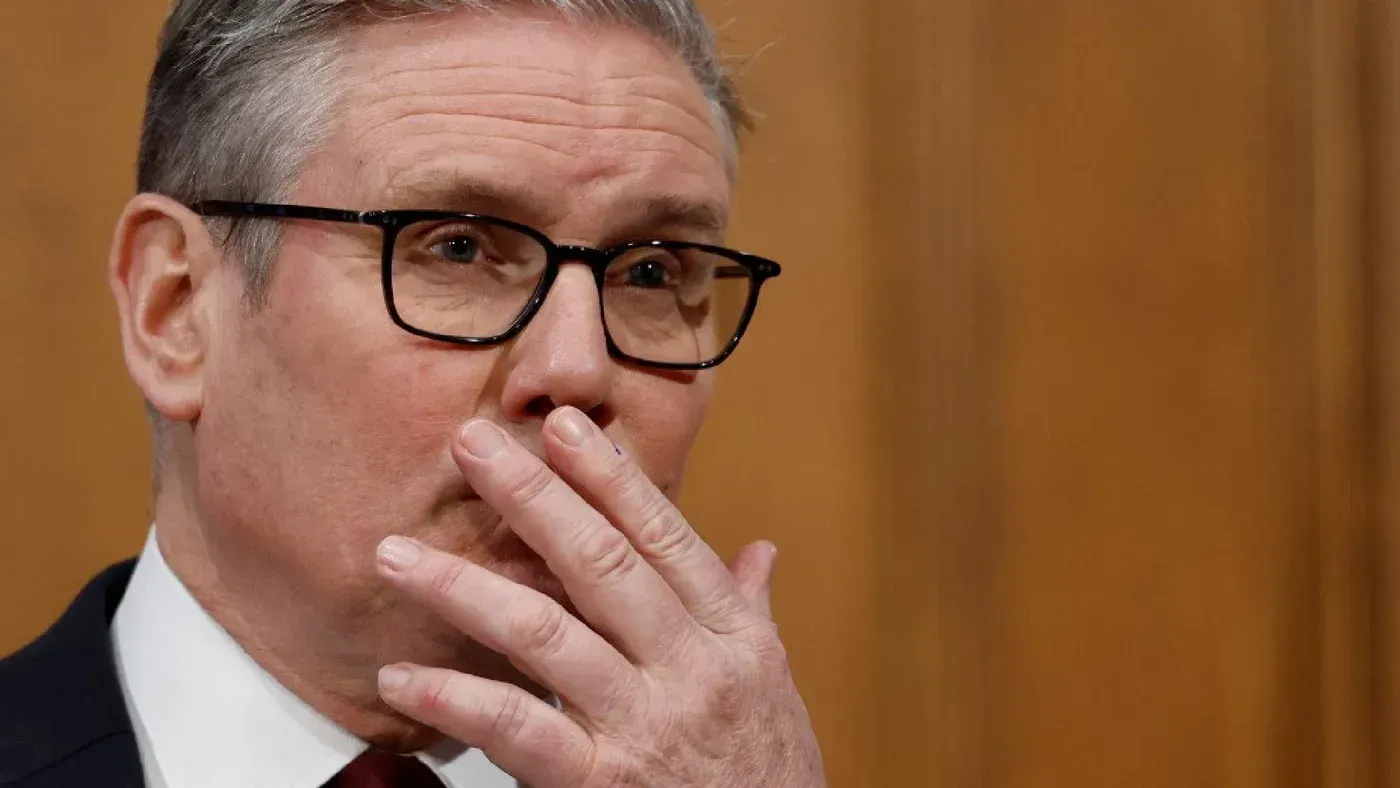 كير ستارمر، رئيس وزراء المملكة المتحدة، يظهر في مؤتمر صحفي مع تعبيرات جدية، وسط خلفية خشبية، يناقش القضايا المتعلقة بالضربات العسكرية الأمريكية على إيران.