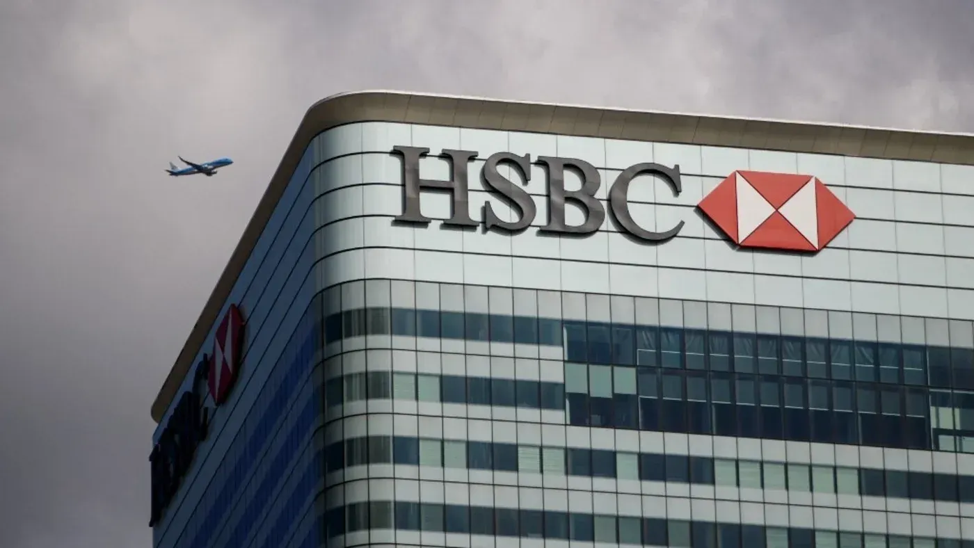 مبنى بنك HSBC مع طائرة تسير في السماء، يرمز إلى التحديات التي تواجه الجمعيات الخيرية الإسلامية في فتح الحسابات المصرفية.