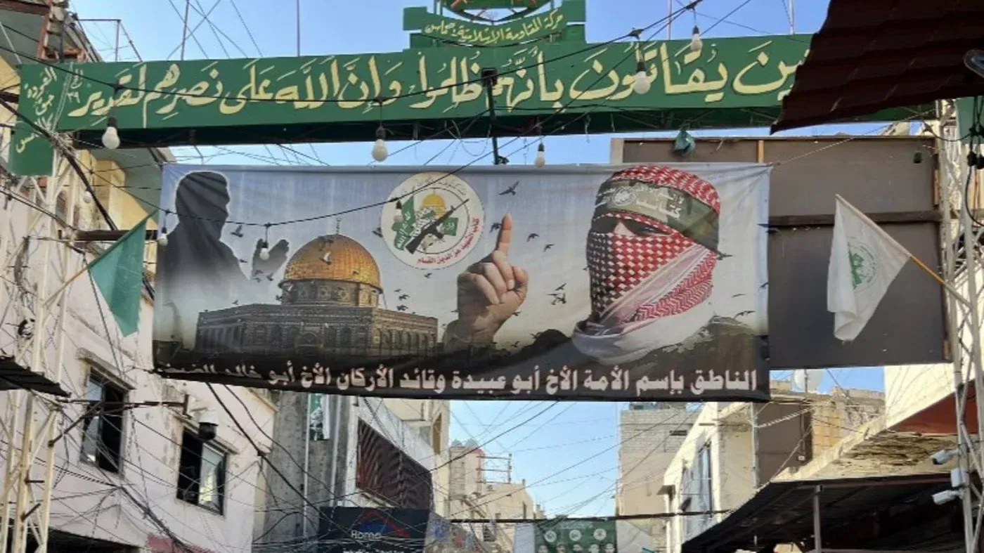 لافتة تحمل صورة لأسد، مع قبة الصخرة في الخلفية، تعبر عن دعم حركة حماس وتظهر رموزها، محاطة بأعلام فلسطينية.