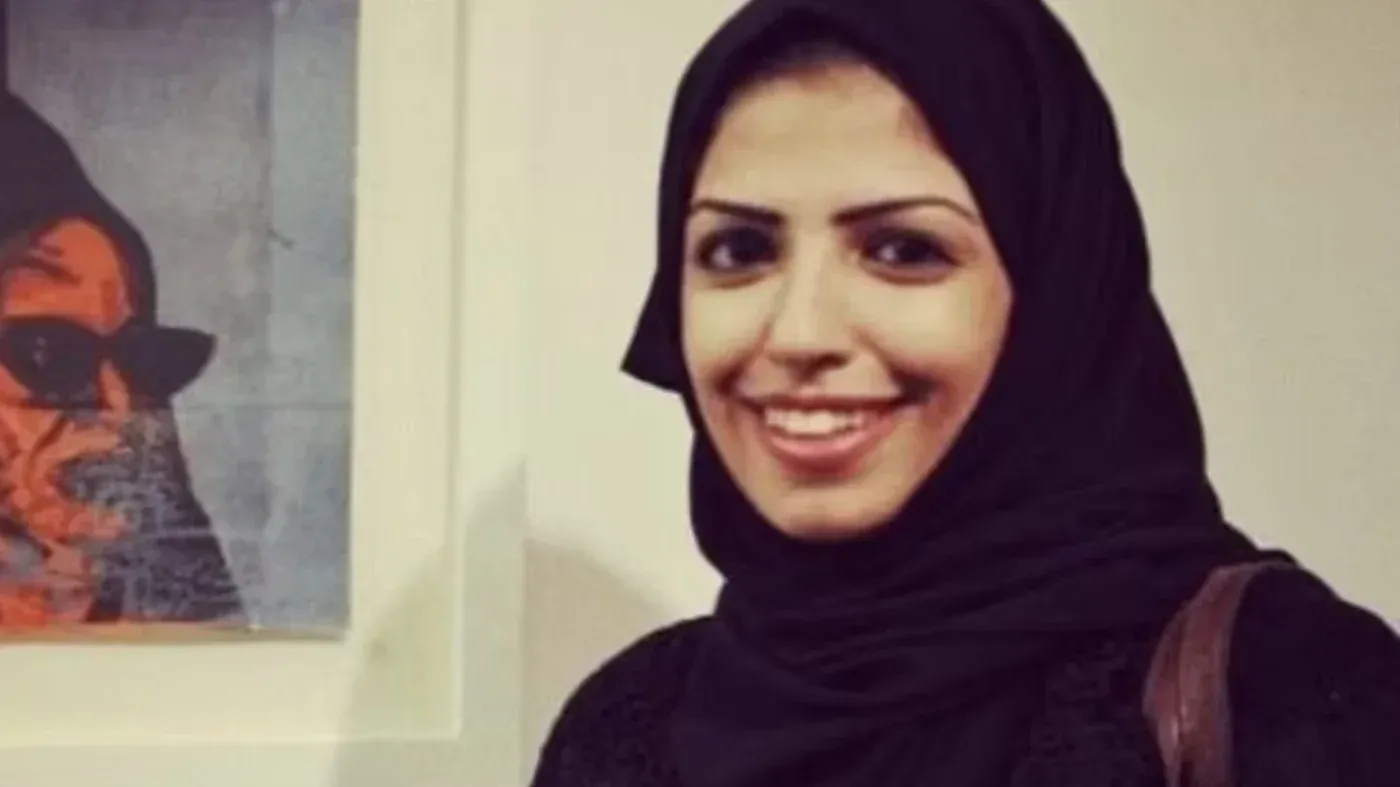 سلمى الشهاب، ناشطة في مجال حقوق الإنسان، تبتسم في صورة، مع خلفية بسيطة، تعكس قضايا حرية التعبير في السعودية.