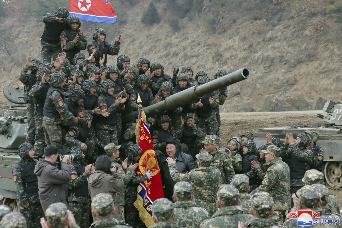 جنود كوريون شماليون يرتدون زيًا عسكريًا، يحتفلون حول مدفع، مع العلم الكوري الشمالي في الخلفية، في سياق دعمهم للقوات الروسية.