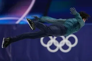 متزلج أوكراني في الهواء أثناء أداء حركته في برنامج التزلج على الجليد الأولمبي، مع التركيز على تقنيته وأسلوبه المميز.