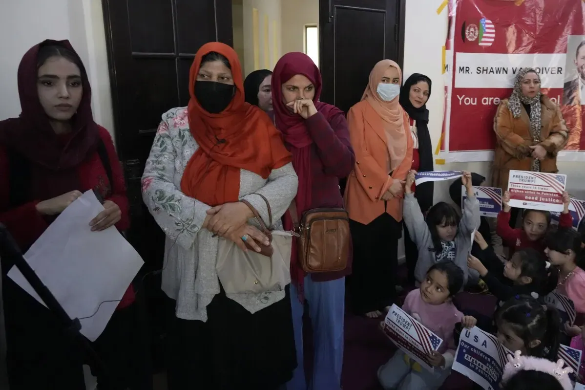 نساء وأطفال أفغان ينتظرون في إسلام أباد، مع لافتات تطالب بالعدالة، في ظل القلق من ترحيل اللاجئين إلى أفغانستان.