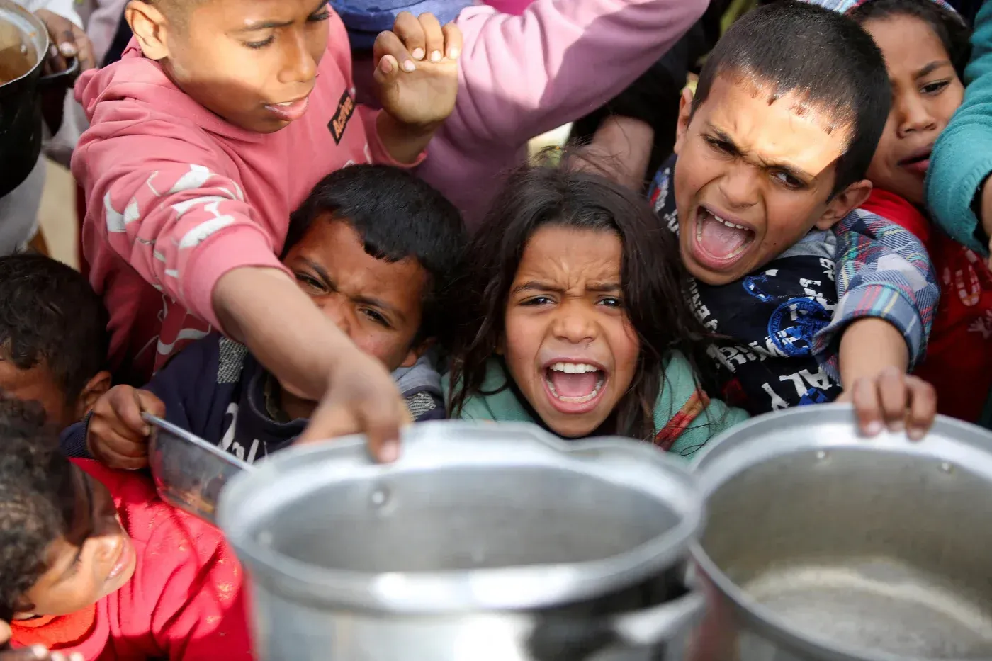 أطفال فلسطينيون يتجمعون بحماس للحصول على المساعدات الغذائية في غزة، معبرين عن معاناتهم في ظل الحصار المستمر.