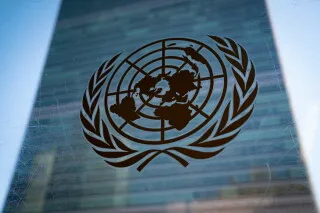 شعار الأمم المتحدة مع خلفية زجاجية، يعكس التحذيرات من أزمة الجوع الناتجة عن الحرب في الشرق الأوسط وتأثيرها على الأمن الغذائي العالمي.