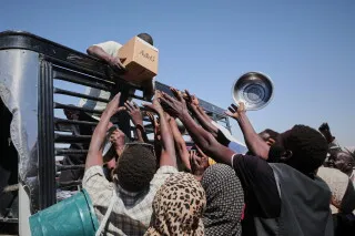مدنيون سودانيون يمدون أيديهم لاستلام مساعدات إنسانية في الأبيض وسط أزمة غذاء حادة بسبب النزاع المسلح.