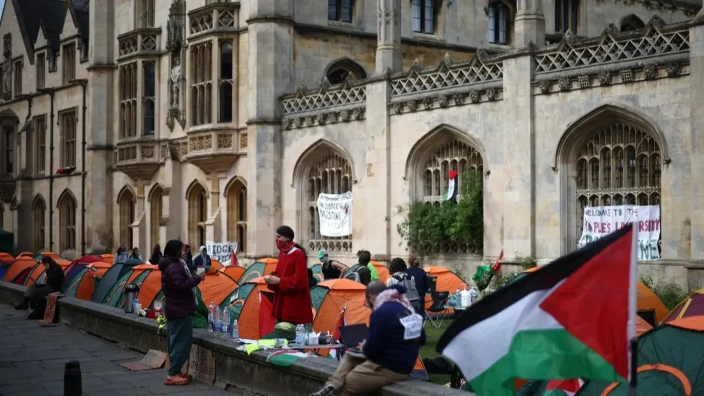 مظاهرة لطلاب جامعة كامبريدج المؤيدين لفلسطين، مع tents ملونة وعلم فلسطيني، تعبيرًا عن مطالبهم بالشفافية في استثمارات الجامعة.