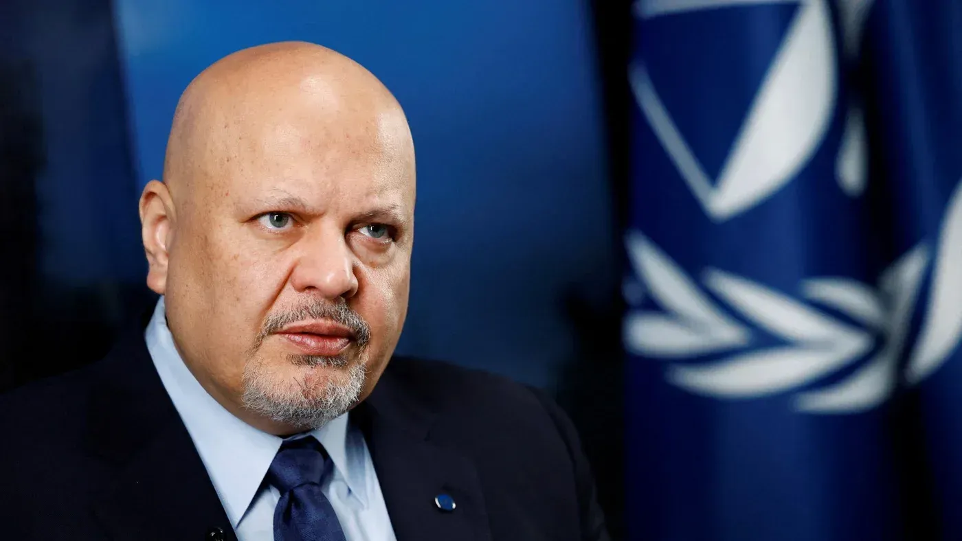 صورة لرئيس المحكمة الجنائية الدولية، كريم خان، أثناء حديثه، مع العلم الخاص بالمحكمة خلفه، في سياق العقوبات الأمريكية ضد المحكمة.