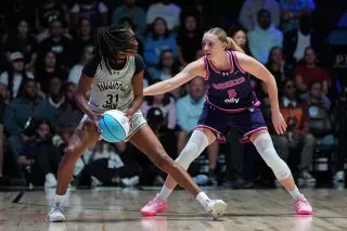 لاعبة كرة سلة تتنافس في مباراة احترافية، مع وجود جمهور خلفها في ملعب مزدحم، مما يعكس عودة كرة السلة النسائية إلى فيلادلفيا.