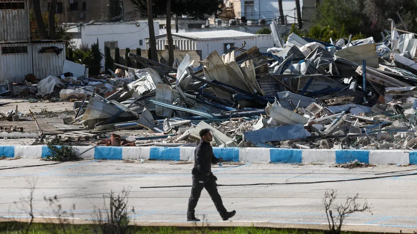 حطام مبنى وكالة الأونروا في حي الشيخ جراح بالقدس بعد الهجوم، مع وجود شخص يمشي في الموقع. يشير الحادث إلى التوترات المستمرة في المنطقة.