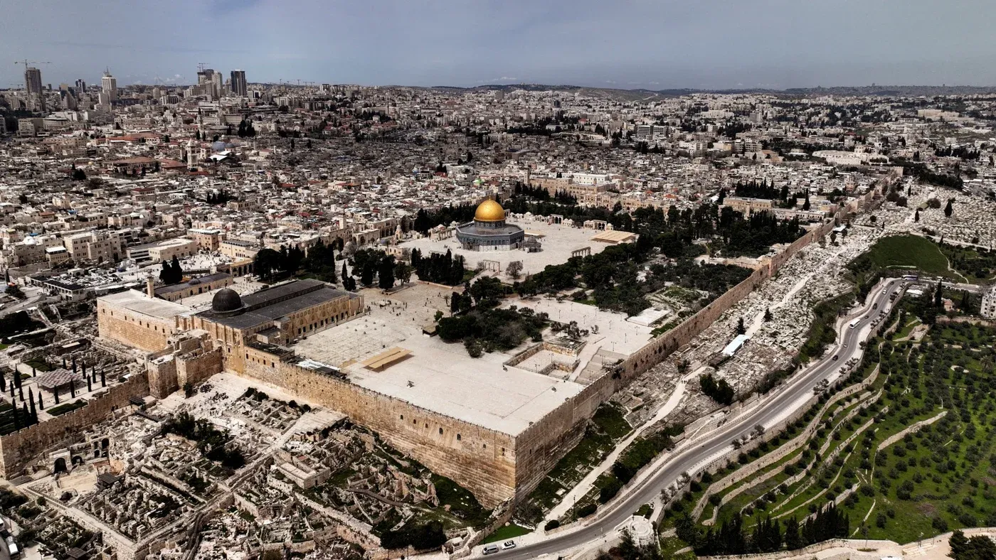 صورة جوية تظهر المسجد الأقصى في القدس، مع قبة الصخرة الذهبية، محاطًا بالمدينة القديمة والمناطق المحيطة، تعكس الأهمية الدينية والسياسية للموقع.