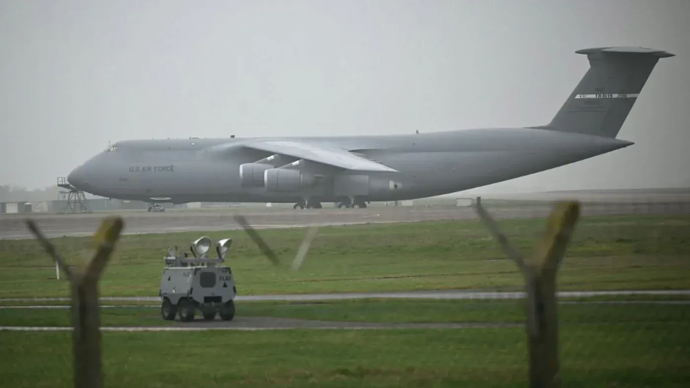هبوط طائرة شحن C-5 Galaxy التابعة لسلاح الجو الأمريكي في قاعدة فيرفورد، مع وجود مركبة عسكرية على المدرج.