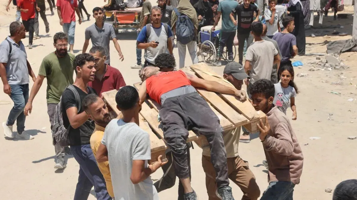 مجموعة من الرجال يحملون شخصًا مصابًا على نقالة في غزة، وسط حشود من الناس، في سياق أزمة إنسانية متصاعدة.