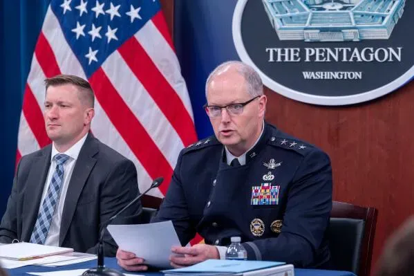 اجتماع في البنتاغون حيث يتحدث مسؤول عسكري عن ميزانية الدفاع، مع العلم الأمريكي وشعار البنتاغون في الخلفية.