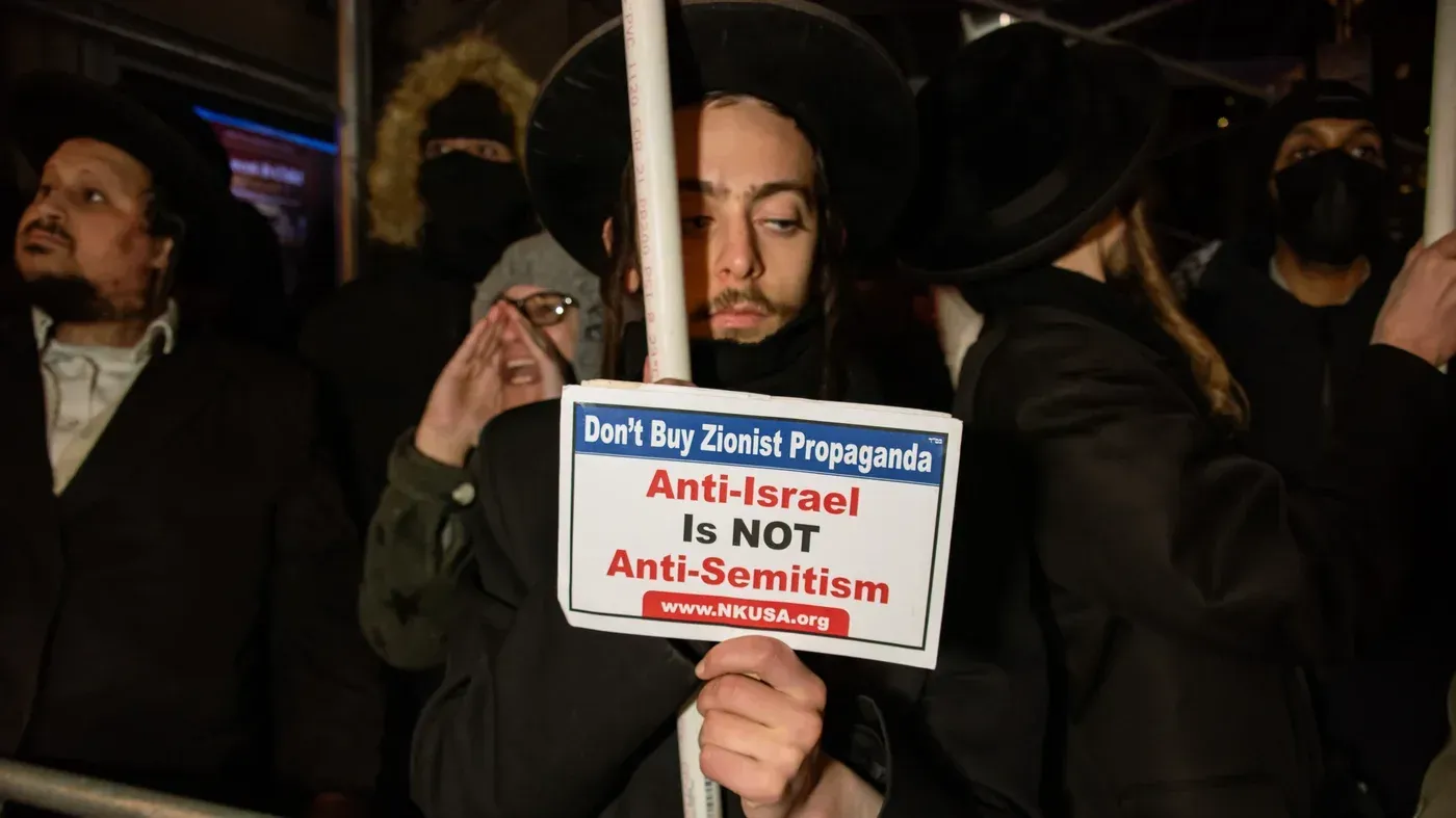 متظاهر يحمل لافتة تعبر عن رفضه للسياسات الصهيونية، وسط تجمع للاحتجاج على بيع الأراضي الفلسطينية في نيويورك.