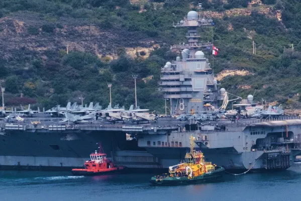 حاملة الطائرات الأمريكية USS Abraham Lincoln ترسو قرب الساحل مع طائرات مقاتلة على سطحها، في مشهد يعكس الضغط المتزايد على حاملات الطائرات الأمريكية بسبب النزاع مع إيران وتأثيره على الوجود الأمريكي في المحيط الهادئ.