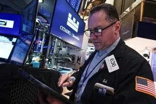 تاجر في بورصة نيويورك يتابع الأسواق المالية، مع شاشات تعرض بيانات الأسهم، في ظل ارتفاع مؤشرات السوق بعد تراجع ترامب عن الرسوم الجمركية.