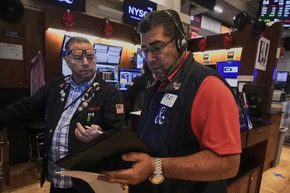 مستثمرون يتبادلون المعلومات في بورصة نيويورك، مع شاشات تعرض بيانات السوق، وسط تراجع الأسهم الأمريكية.