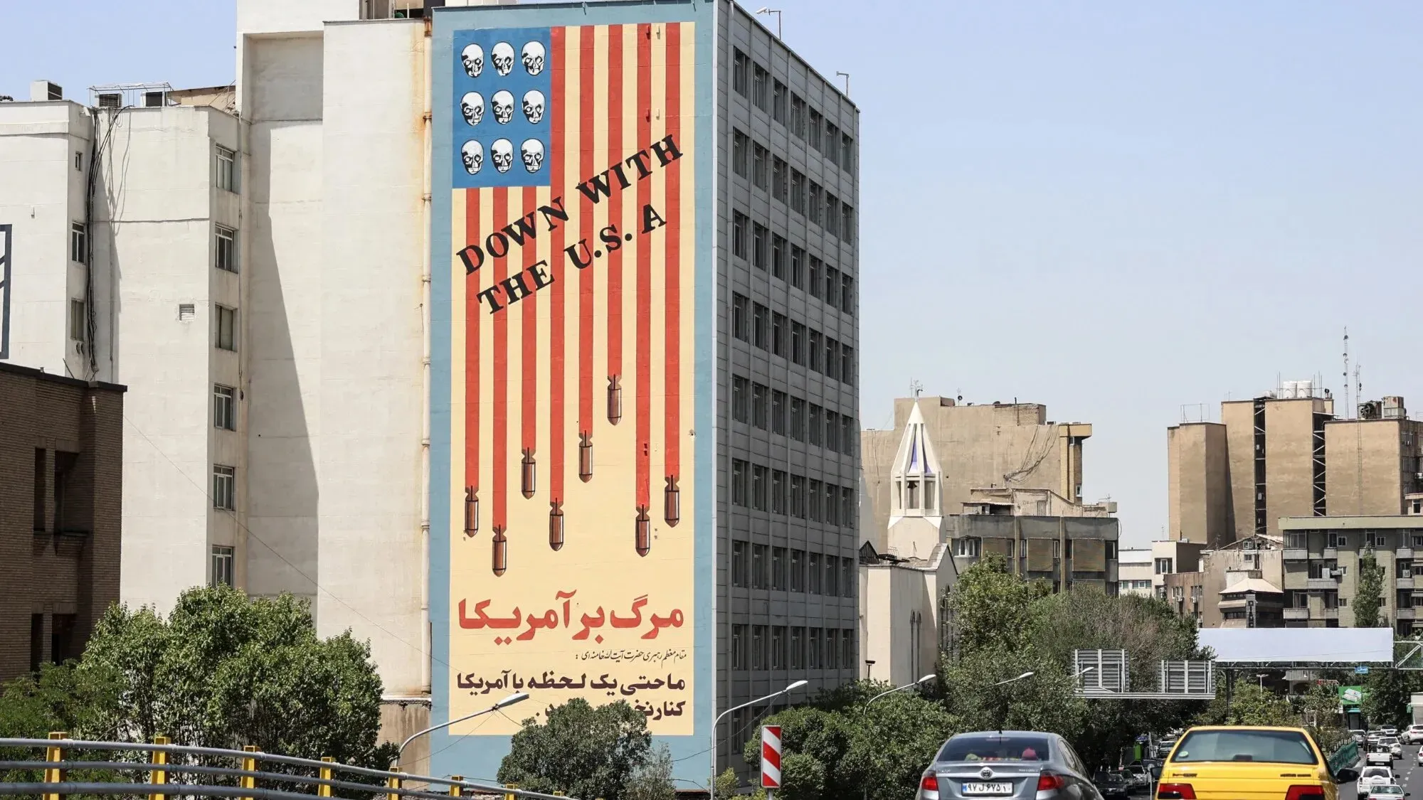 لافتة كبيرة في طهران تحمل عبارة "الموت لأمريكا" مع رسومات توضح أسلحة وصور جماجم، تعكس مشاعر معارضة تجاه الولايات المتحدة.