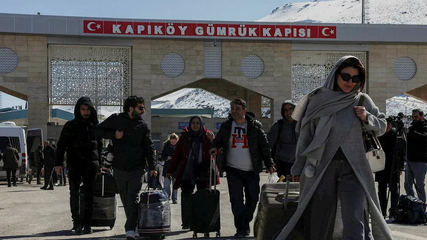 المسافرون يتجهون نحو بوابة كابيكوي الحدودية التركية، مع حقائبهم، في مشهد يعكس الحركة النشطة على الحدود.
