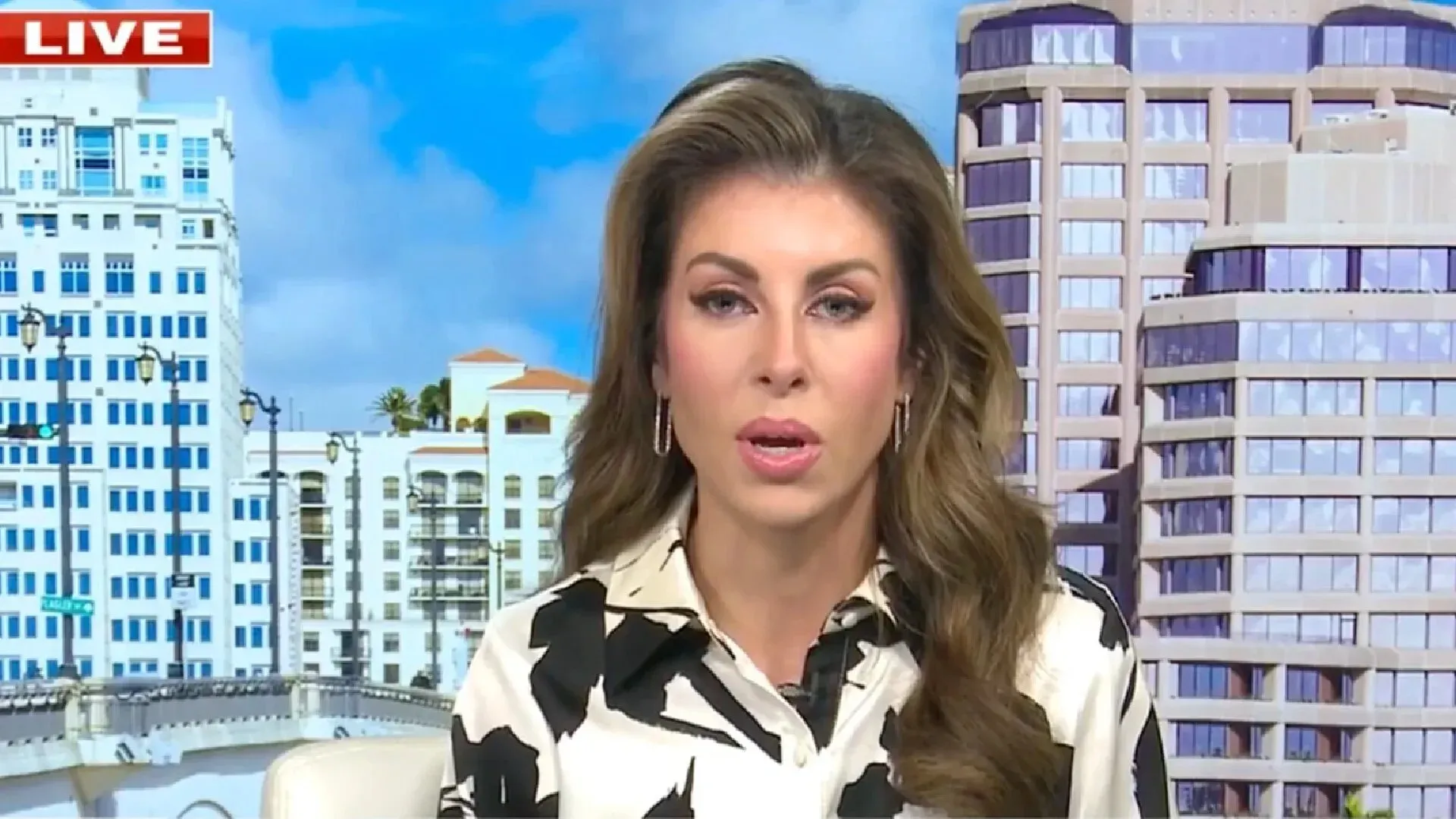 مورغان أورتاغوس تتحدث في برنامج مباشر، مع خلفية لمباني حديثة، حول دعم الولايات المتحدة لإسرائيل في صراعها مع غزة.