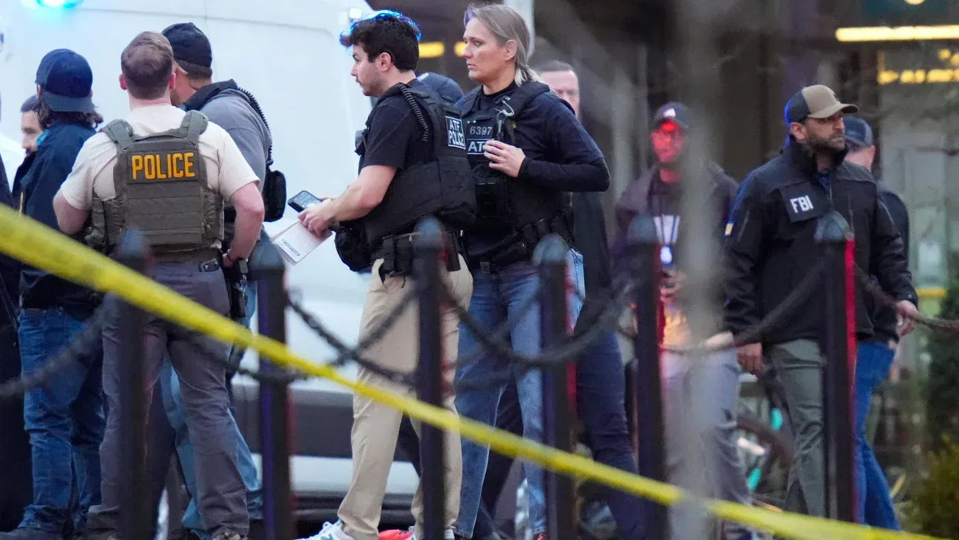 تواجد عناصر من الشرطة الفيدرالية والشرطة المحلية في موقع حادث إطلاق نار في واشنطن، مع وجود شريط أمني حول المنطقة.