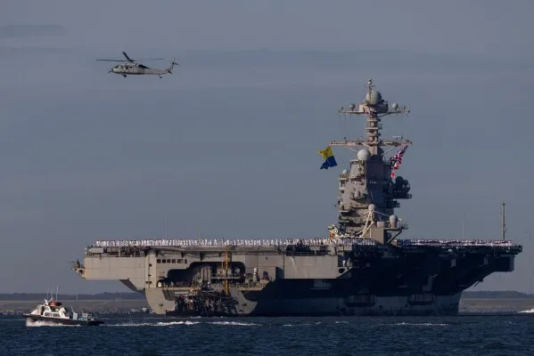 حاملة الطائرات USS Gerald R. Ford ترسو في قاعدة نورفولك البحرية بعد انتشار استمر 11 شهراً، مع مروحيات وسفينة مرافقة.