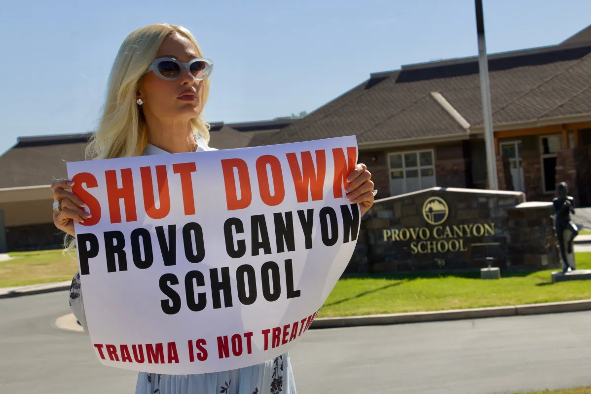 باريس هيلتون تحمل لافتة تطالب بإغلاق مدرسة Provo Canyon بسبب سوء المعاملة والإهمال في رعاية المراهقين.