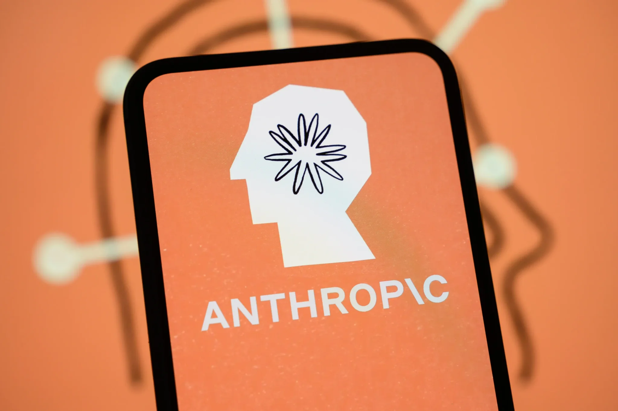 شعار شركة Anthropic على شاشة هاتف ذكي مع خلفية برتقالية، يرمز لمناقشة استثمارات أمازون وجوجل في الذكاء الاصطناعي والحوسبة السحابية.