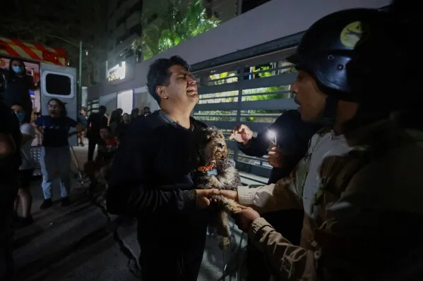 رجل يحمل كلبه في حالة من الفزع بعد الزلزالين العنيفين في فنزويلا، حيث تجمهر الناس في الشوارع بحثًا عن الأمان.