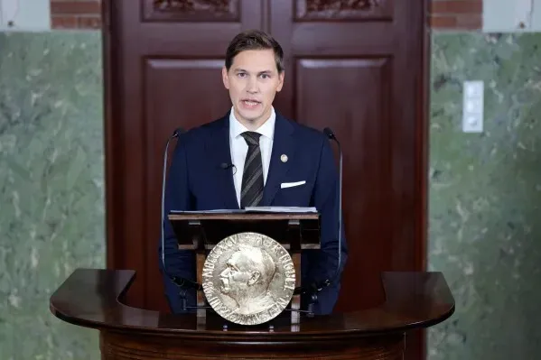 رئيس لجنة نوبل النرويجية يتحدث في حفل إعلان فوز ماريا كورينا ماتشادو بجائزة نوبل للسلام، مع وجود ميدالية نوبل على المنصة.