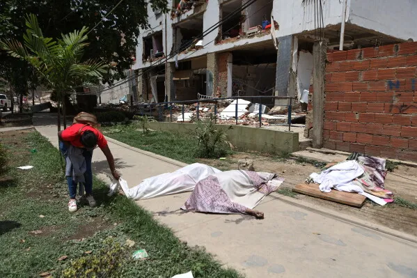 شخص يحمل غطاءً فوق جثة في موقع زلزال مدمر، مع خلفية لمباني مدمرة في فنزويلا، تعبير عن الألم والمعاناة بعد الكارثة.