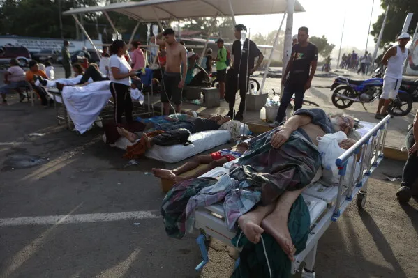 مصابون يتلقون العلاج في الهواء الطلق بعد الزلازل المدمّرة في فنزويلا، مع وجود أفراد من المجتمع المحلي يساعدون في تقديم الدعم.