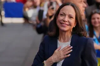 ماريا كورينا ماتشادو، زعيمة المعارضة الفنزويلية، تبتسم وتضع يدها على قلبها خلال تجمّع حاشد في مدريد، محاطة بالمعجبين.