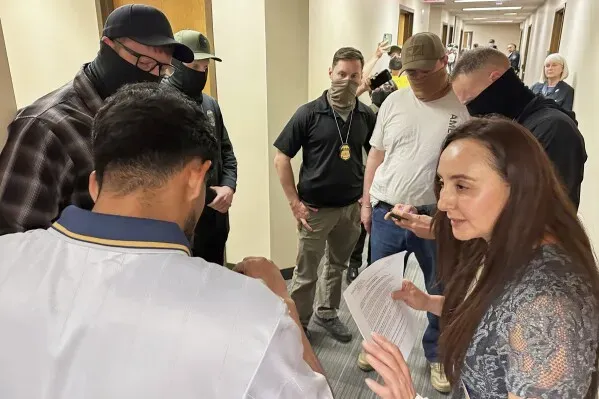 مجموعة من المتطوعين تساعد رجل كولومبي في محكمة الهجرة، بينما يتواجد عملاء من وكالة إنفاذ قوانين الهجرة والجمارك في الجوار.