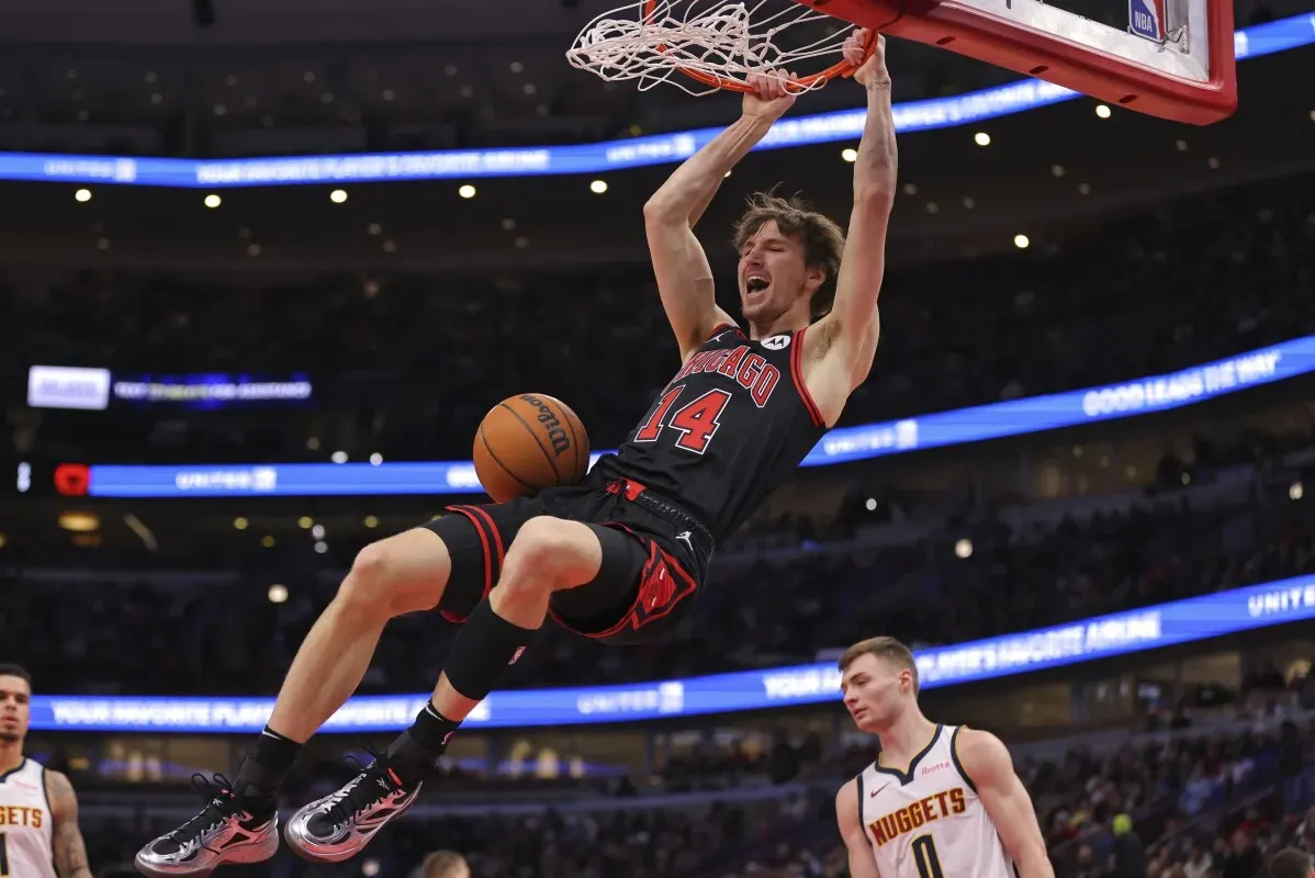 لاعب كرة سلة من فريق شيكاغو بولز يسجل نقطة من خلال dunk، مع وجود لاعب من دنفر ناجتس في الخلفية. المباراة تبرز قوة أداء شيكاغو.