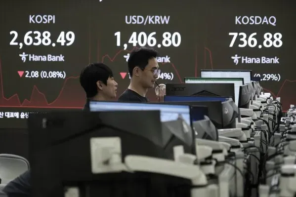 متداولان في مركز مالي يتابعان مؤشرات الأسهم وأسعار الصرف على شاشات الكمبيوتر، مع تراجع الأسواق في ظل تقلبات اقتصادية.