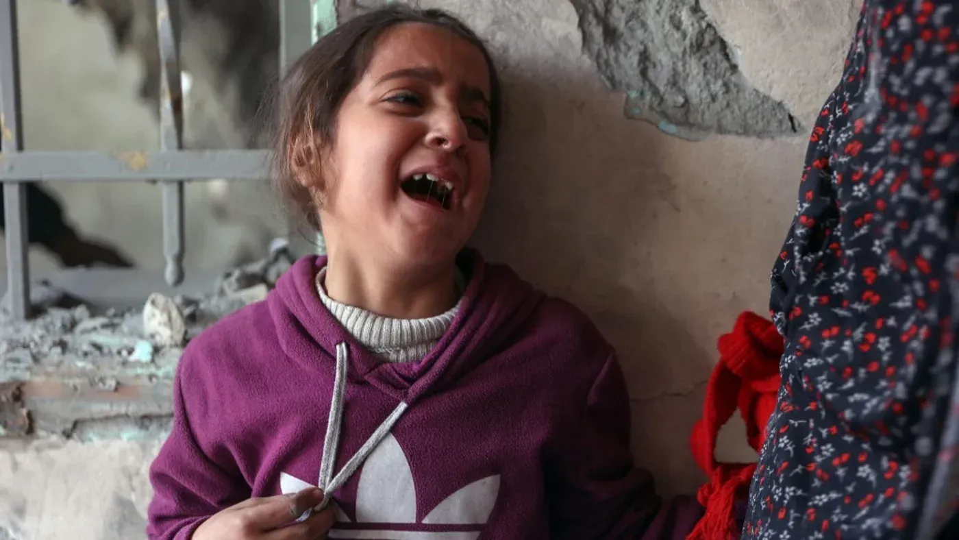 طفلة فلسطينية تبكي في مكان مدمّر، تعبيرًا عن الحزن والألم الناتج عن الصراع المستمر وتأثير الاحتلال على حياتها.