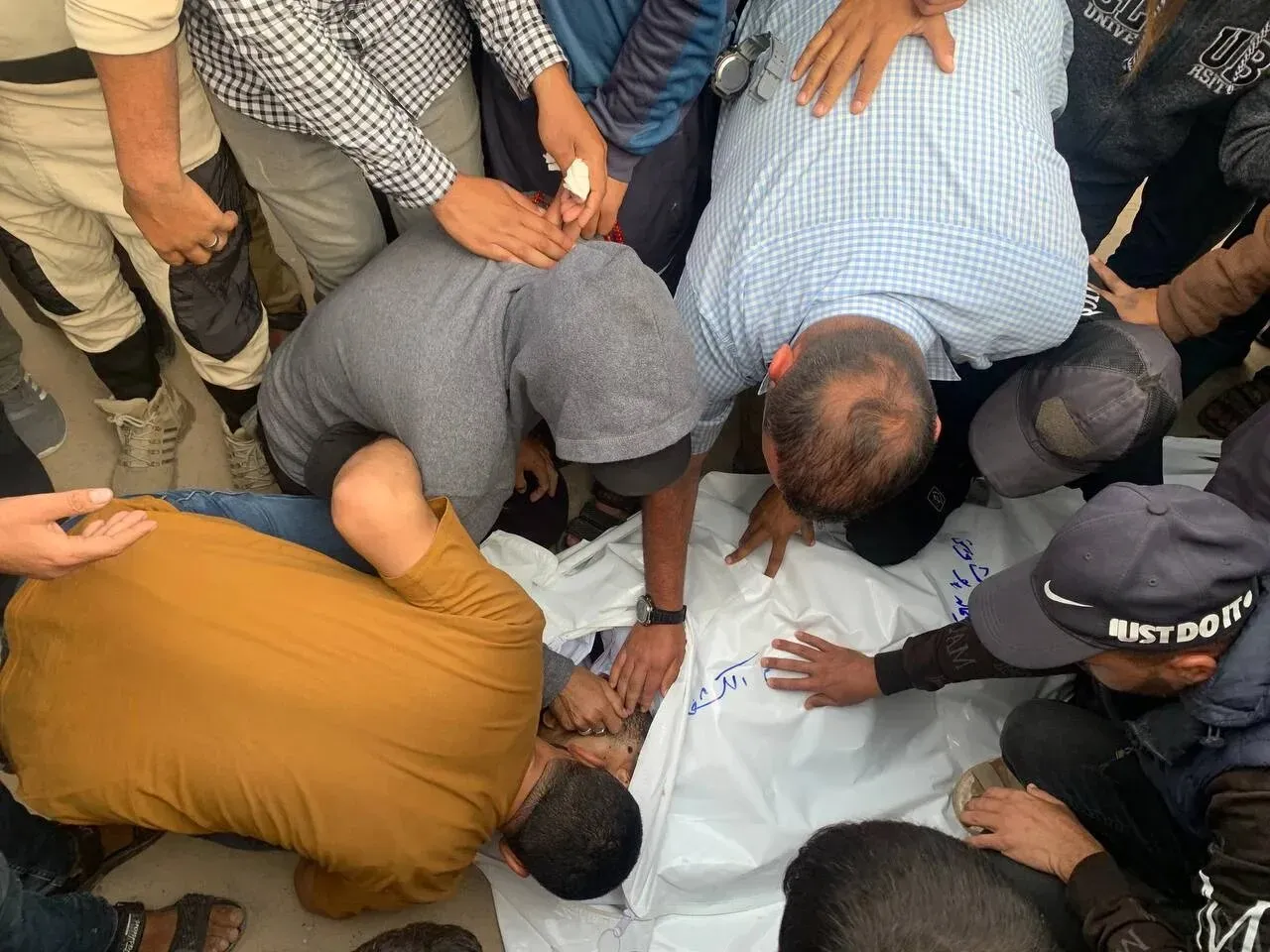 حشود من الناس يحيطون بجثة مغطاة في حي الشجاعية بغزة، بعد غارة إسرائيلية أسفرت عن مقتل العشرات وإصابة الكثيرين.