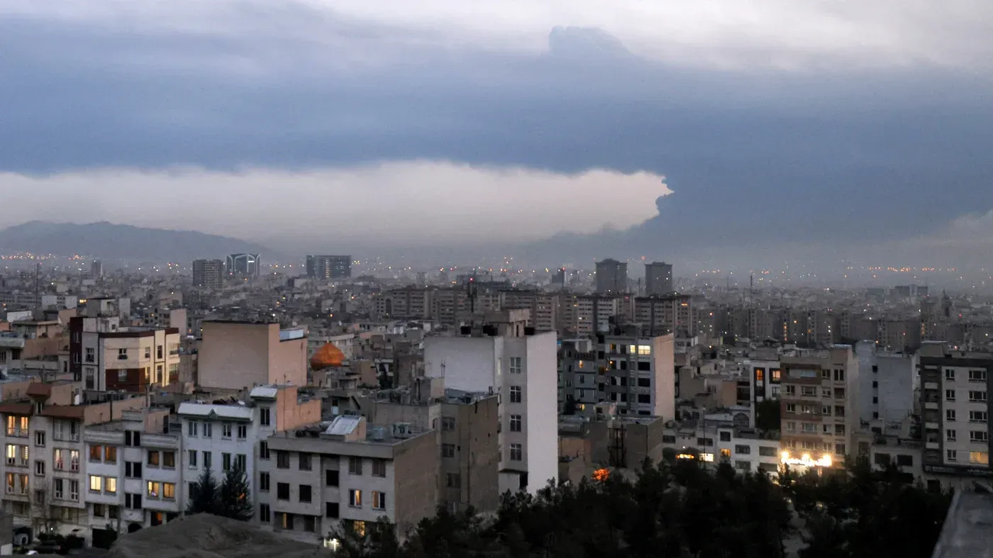منظر عام لمدينة طهران تحت سماء غائمة، يظهر تداخل المباني السكنية مع الأفق الجبلي، مما يعكس التوترات الجيوسياسية في المنطقة.