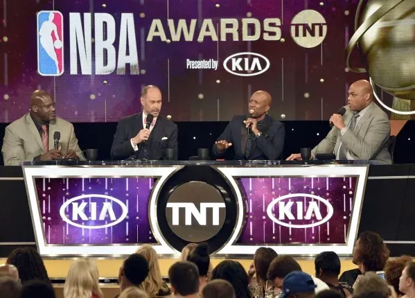 حفل توزيع جوائز NBA على قناة TNT، حيث يظهر أربعة مضيفين يتحدثون أمام جمهور، مع شعار كيا وTNT خلفهم.