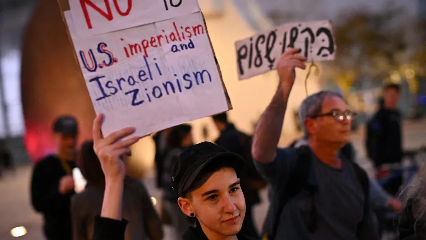 متظاهر يحمل لافتة مكتوب عليها "لا للإمبريالية الأمريكية والصهيونية الإسرائيلية" في احتجاج ضد الحرب في القدس.