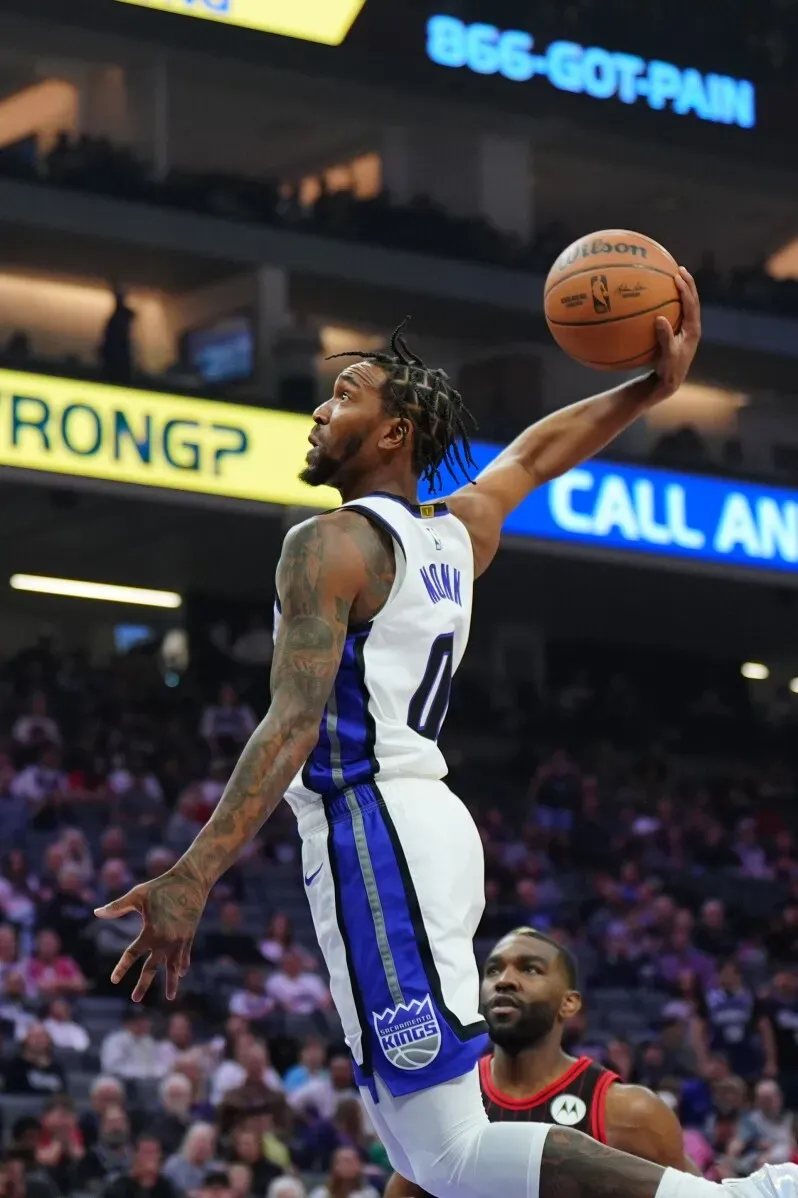 لاعب كرة سلة من فريق ساكرامنتو كينجز يقوم بعملية تسديد مثيرة، بينما يشاهد لاعب من فريق شيكاغو بولز في الخلفية.