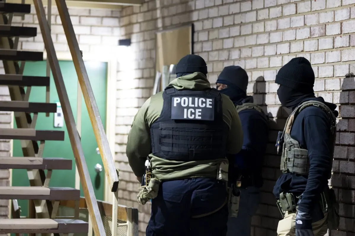 عناصر إنفاذ قوانين الهجرة والجمارك الأميركية (ICE) يتحدثون خلال عملية اعتقال للمهاجرين في منطقة سكنية، مما يعكس زيادة النشاط الأمني تحت إدارة ترامب.