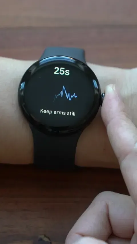ساعة ذكية تعرض رسمًا بيانيًا لنبضات القلب مع تعليمات للحفاظ على اليدين ثابتتين، مما يشير إلى قياس عدم انتظام ضربات القلب.