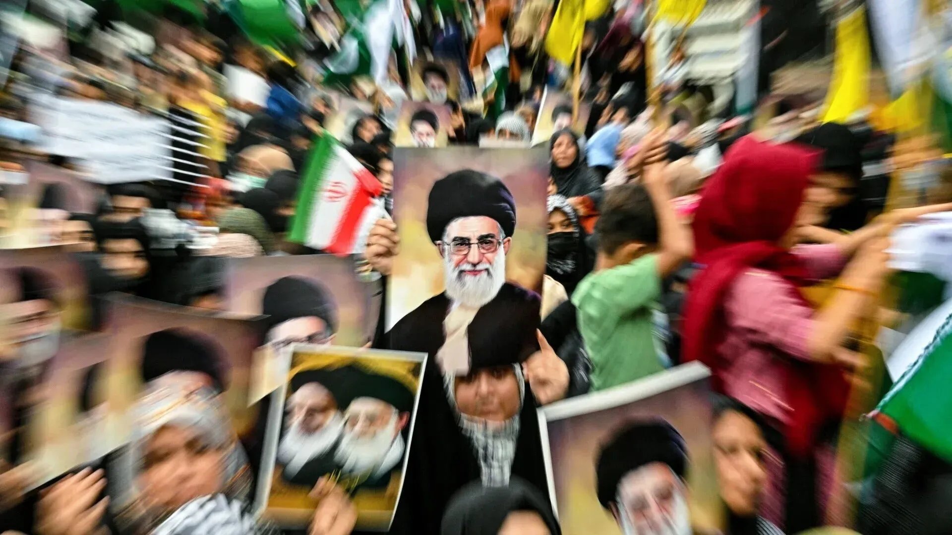 تظهر الصورة حشودًا من المتظاهرين يحملون لافتات وصورًا للمرشد الإيراني علي خامنئي، مع أعلام إيرانية، في احتجاج ضد الضربات الأمريكية والإسرائيلية.