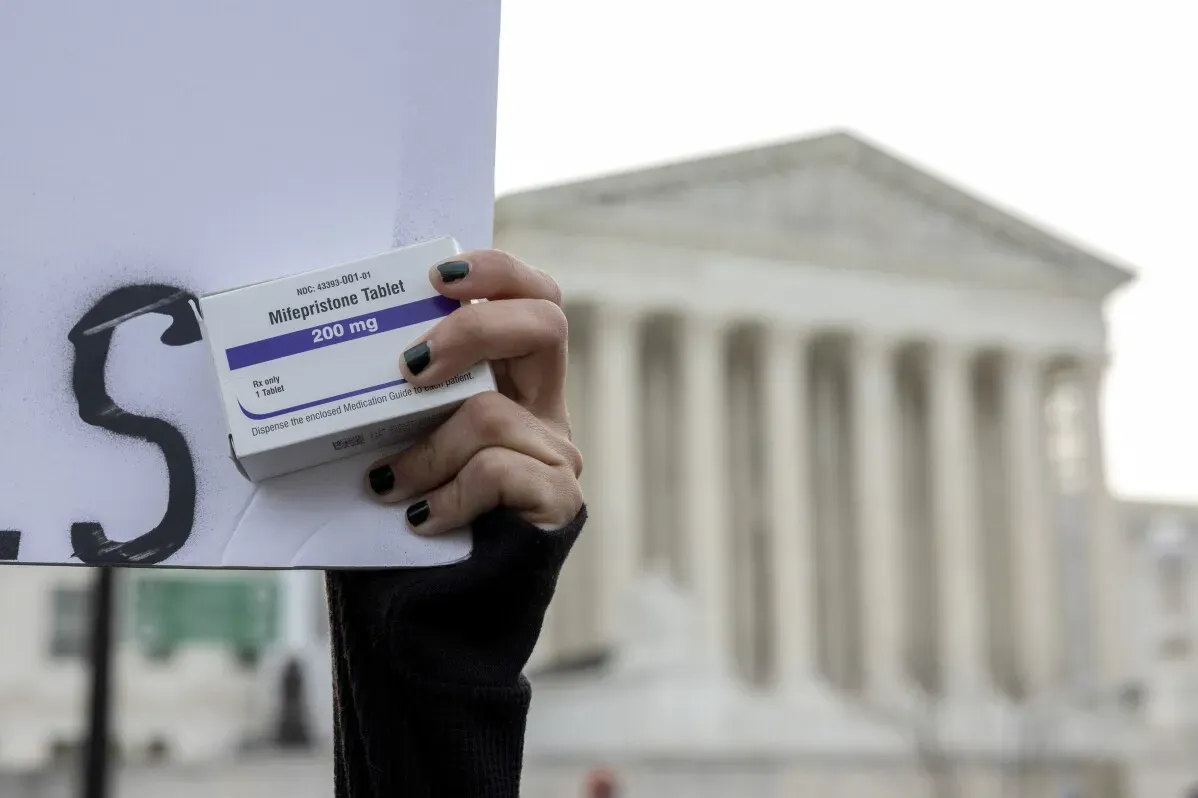 امرأة تحمل عبوة من عقار الميفيبريستون، أمام مبنى المحكمة العليا الأمريكية، في سياق الجدل حول حقوق الإجهاض.