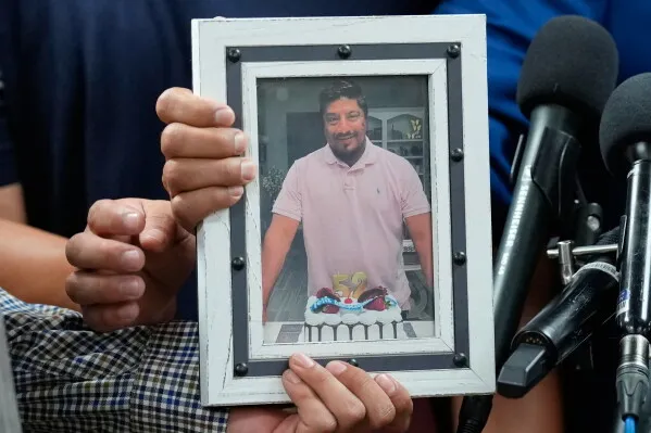 يدان شخصان صورة مؤطرة للورنزو سالغادو أراوخو، المواطن المكسيكي الذي قُتل بإطلاق نار من قبل دائرة الهجرة الأمريكية في هيوستن، وسط احتجاجات ومطالبات بتحقيق مستقل.