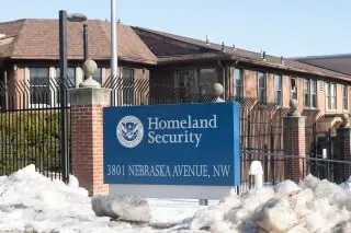 مبنى وزارة الأمن الداخلي في واشنطن، مع لافتة تشير إلى العنوان. يبرز الإغلاق الحكومي وتأثيره على خدمات الهجرة.